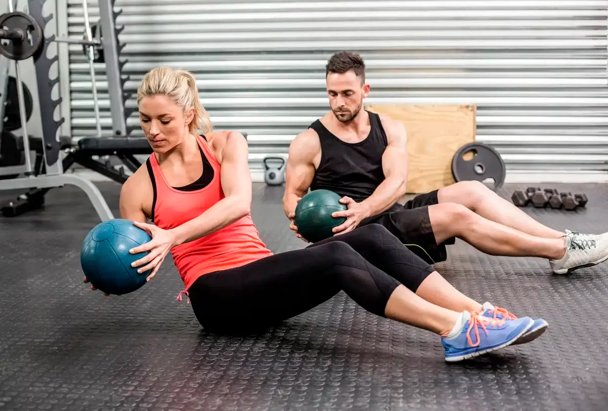 homem e mulher fazendo abdominal com medicine ball