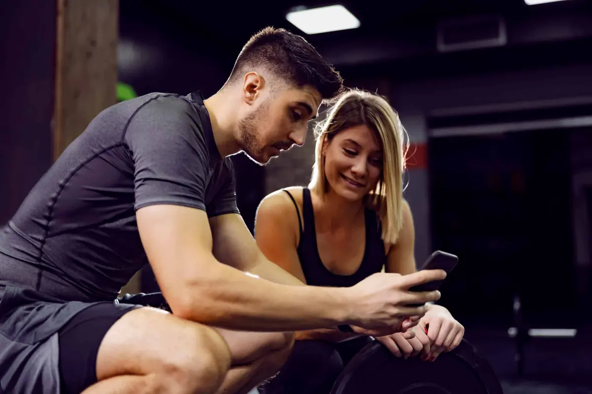casal olhando o celular na academia