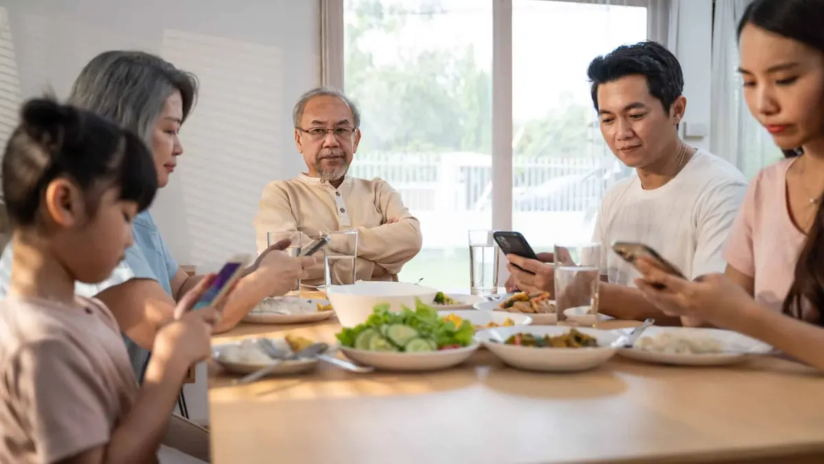 família à mesa usando o celular