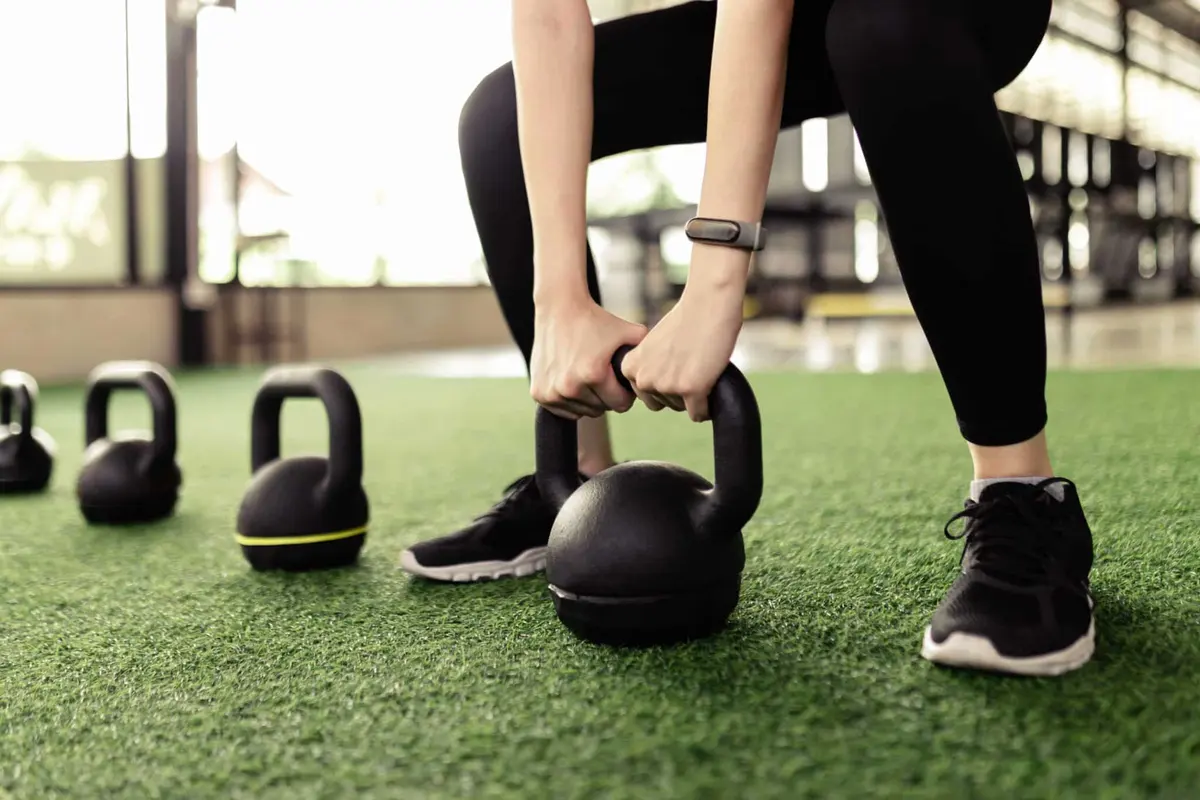 pessoa pegando kettlebell do chão