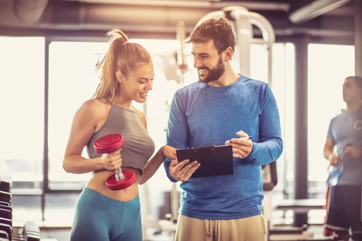 Personal trainer acompanhando uma aluna na academia