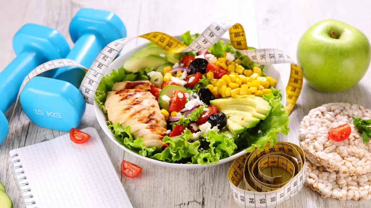 prato de salada com frango ao lado de halteres