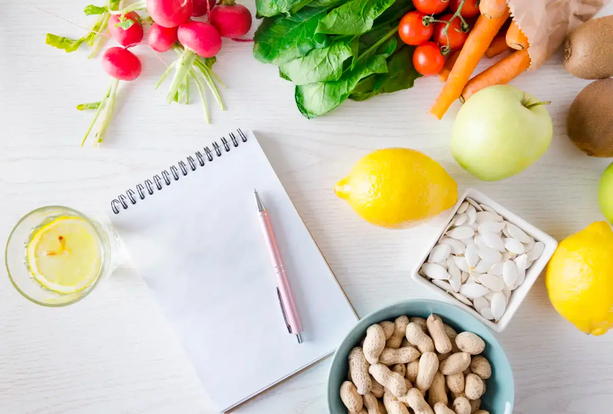 caderno de diário alimentar ao lado de frutas e água