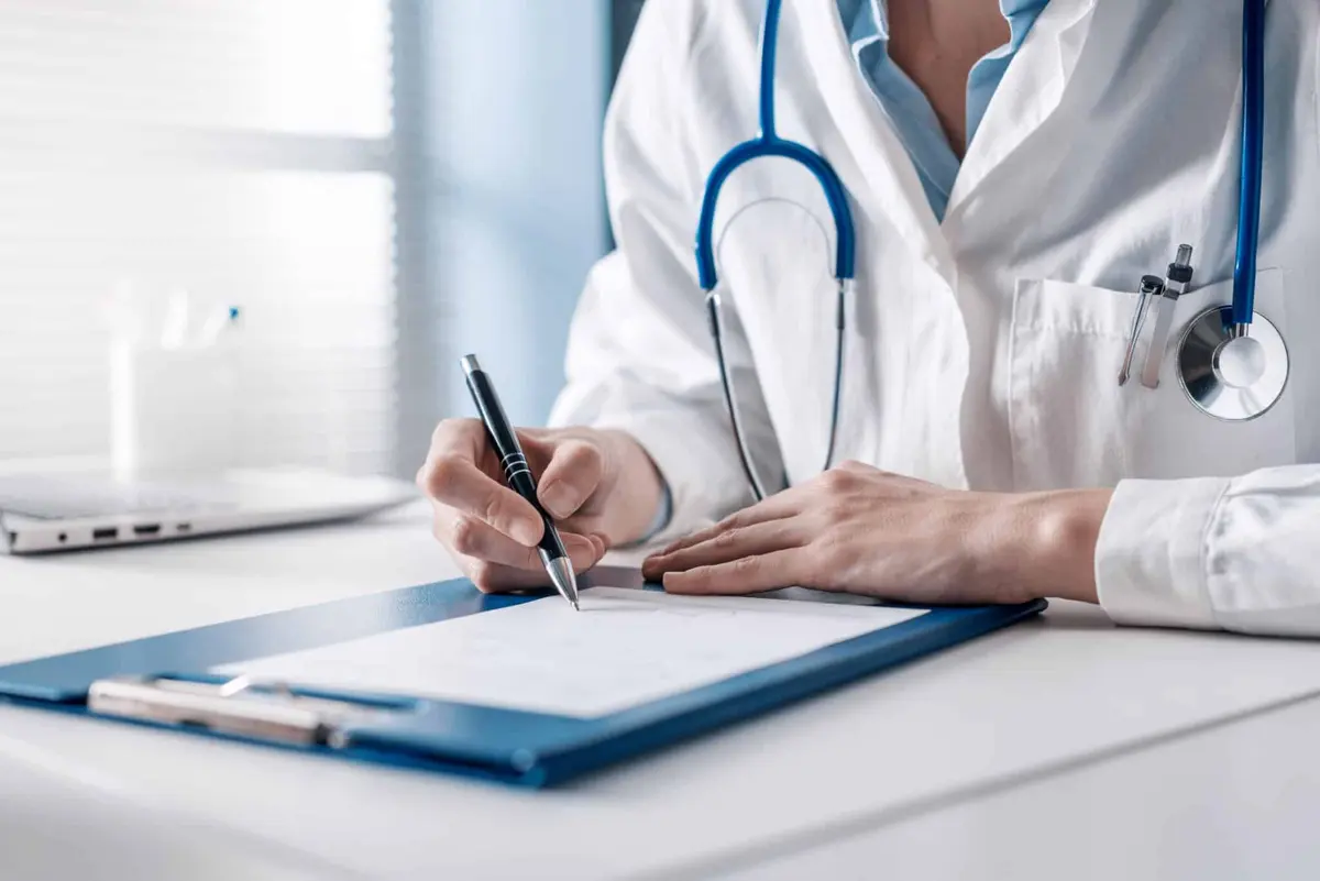 médico escrevendo em uma prancheta