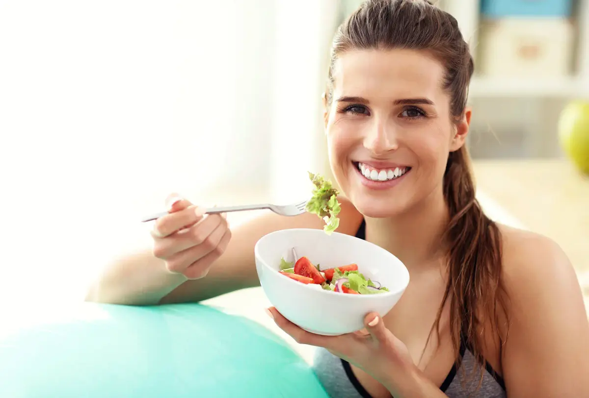 mulher sorrindo comendo salada