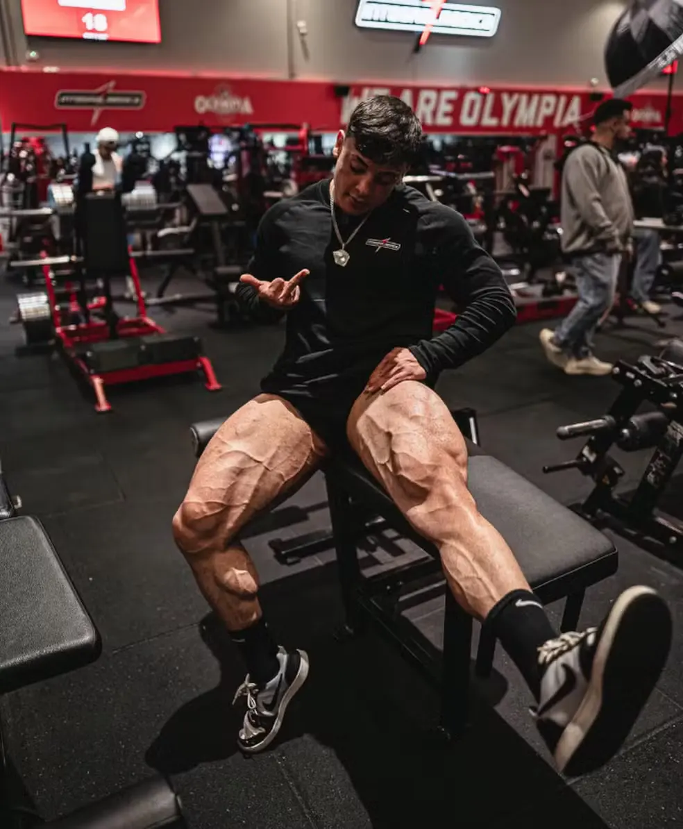 homem com pernas musculosas sentado na academia