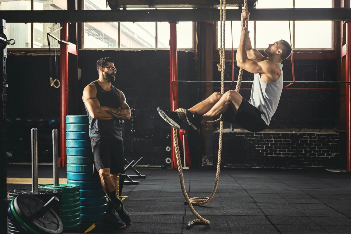 Homem subindo na corda no treino de crossfit