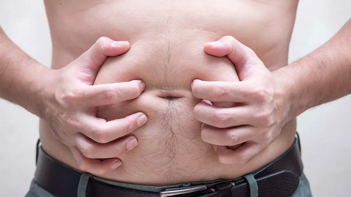 mãos apertando a gordura da barriga