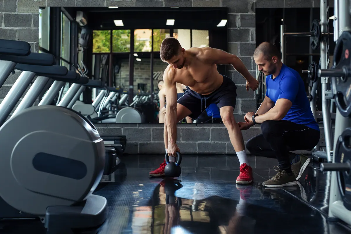 Personal trainer acompanhando um aluno na academia