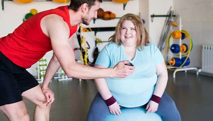 personal trainer orientando mulher com obesidade na academia