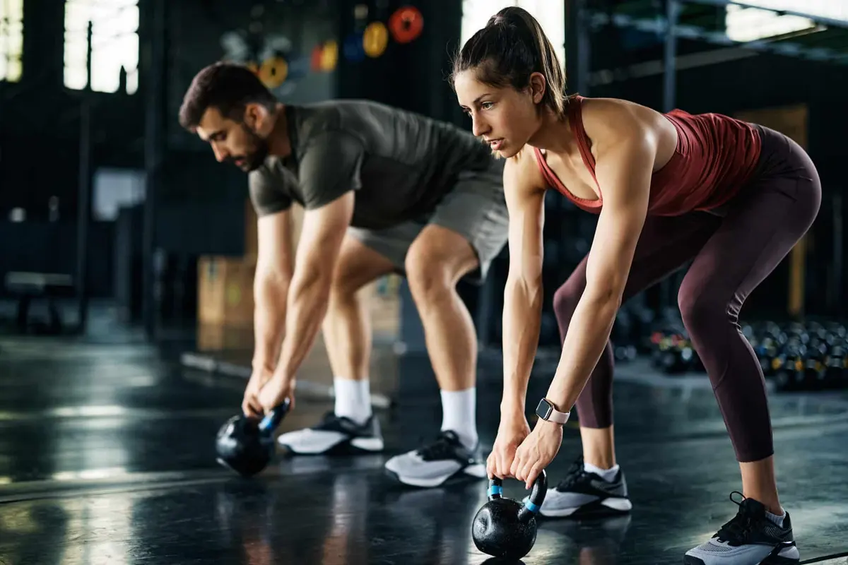 homem e mulher fazendo kettlebell swing