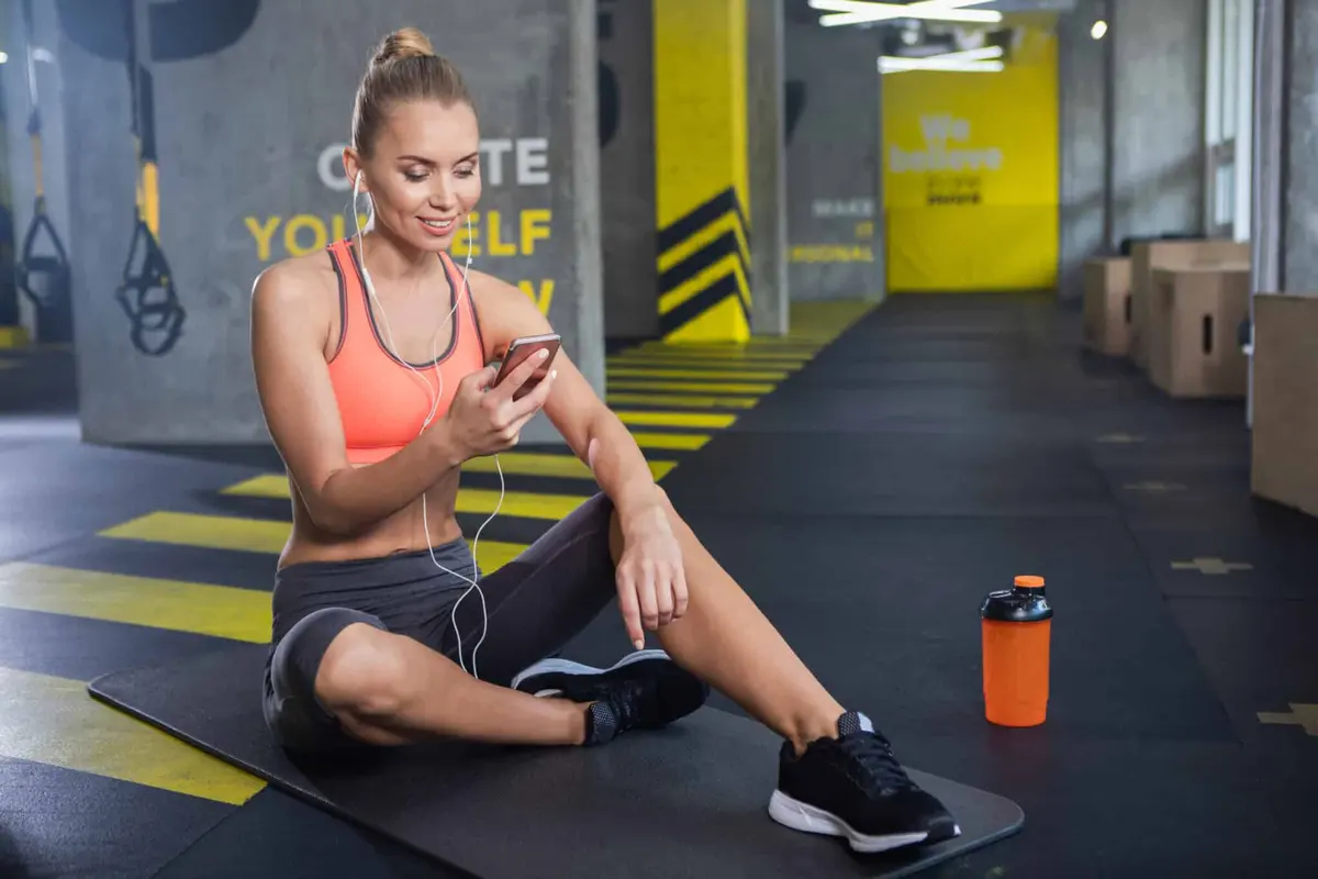 mulher sentada na academia usando o celular