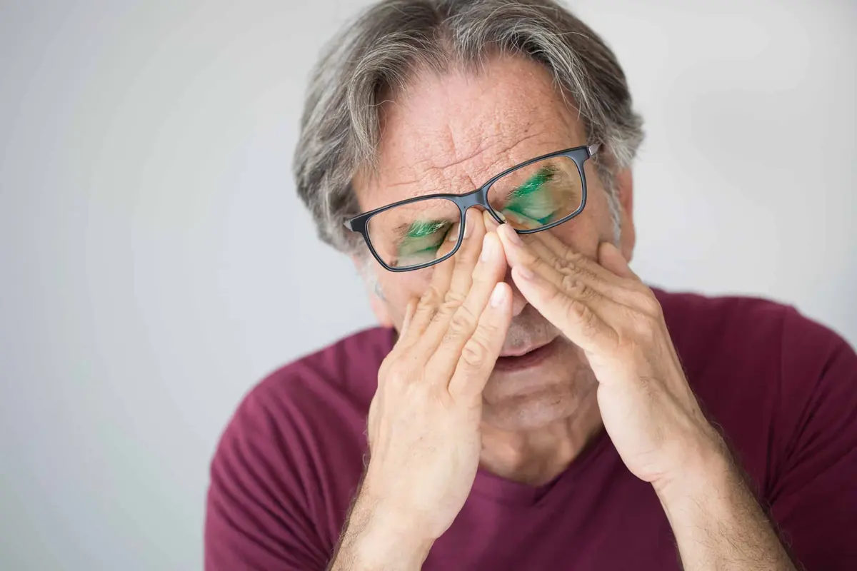 homem cansado esfregando os olhos