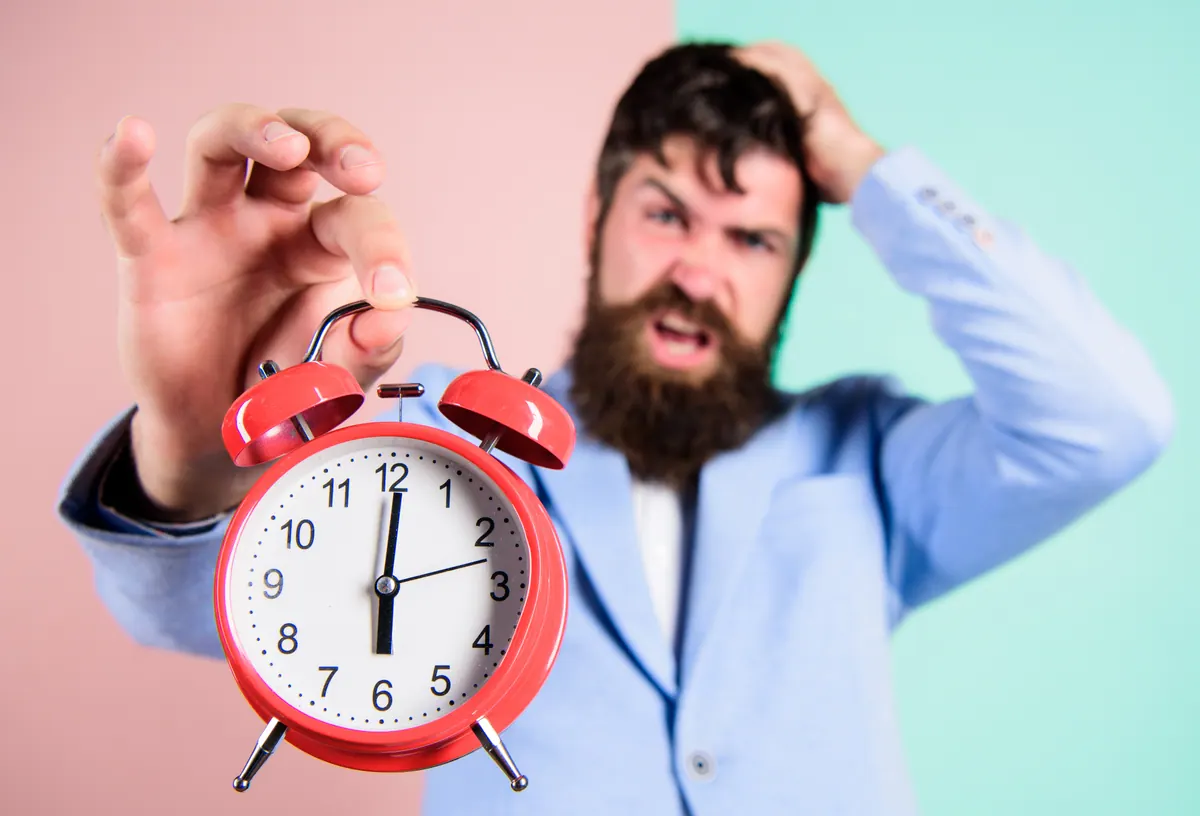 Homem estressado segurando um despertador