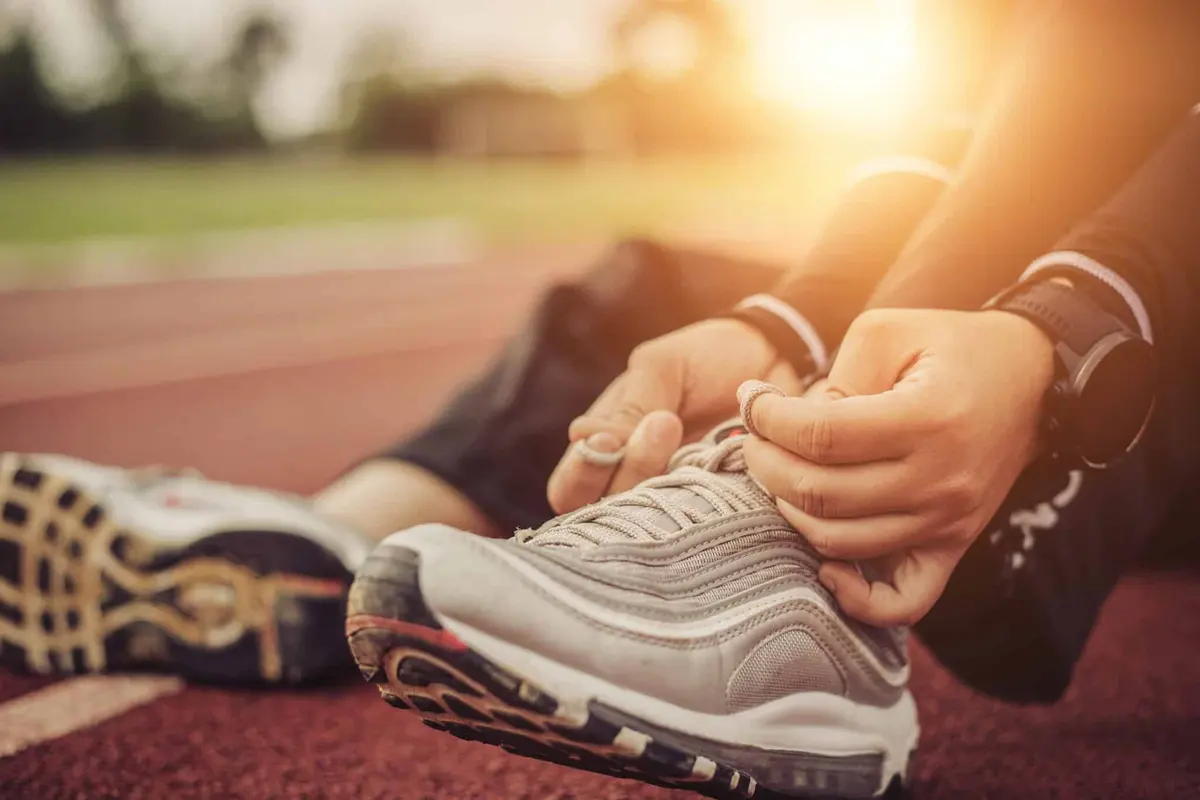 pessoa amarrando o tênis na pista de corrida