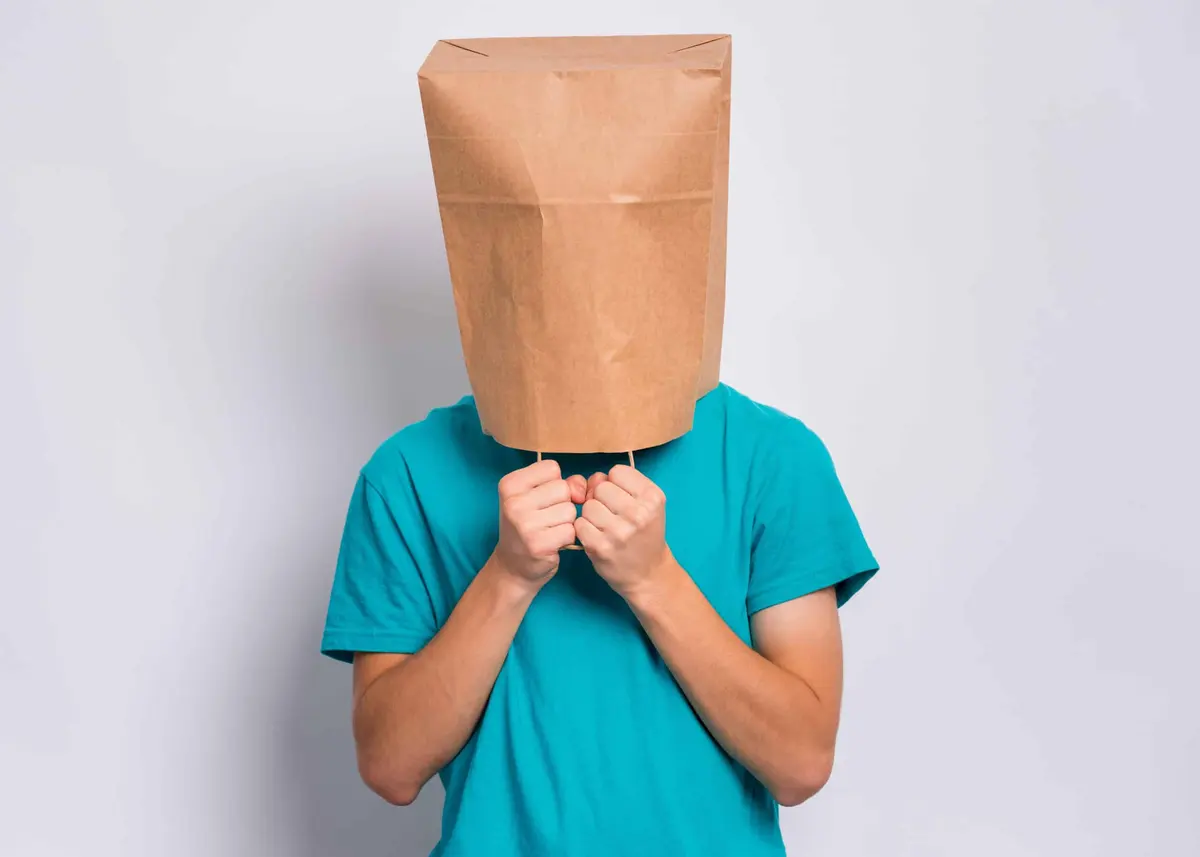 pessoa com um saco de papel na cabeça, com vergonha