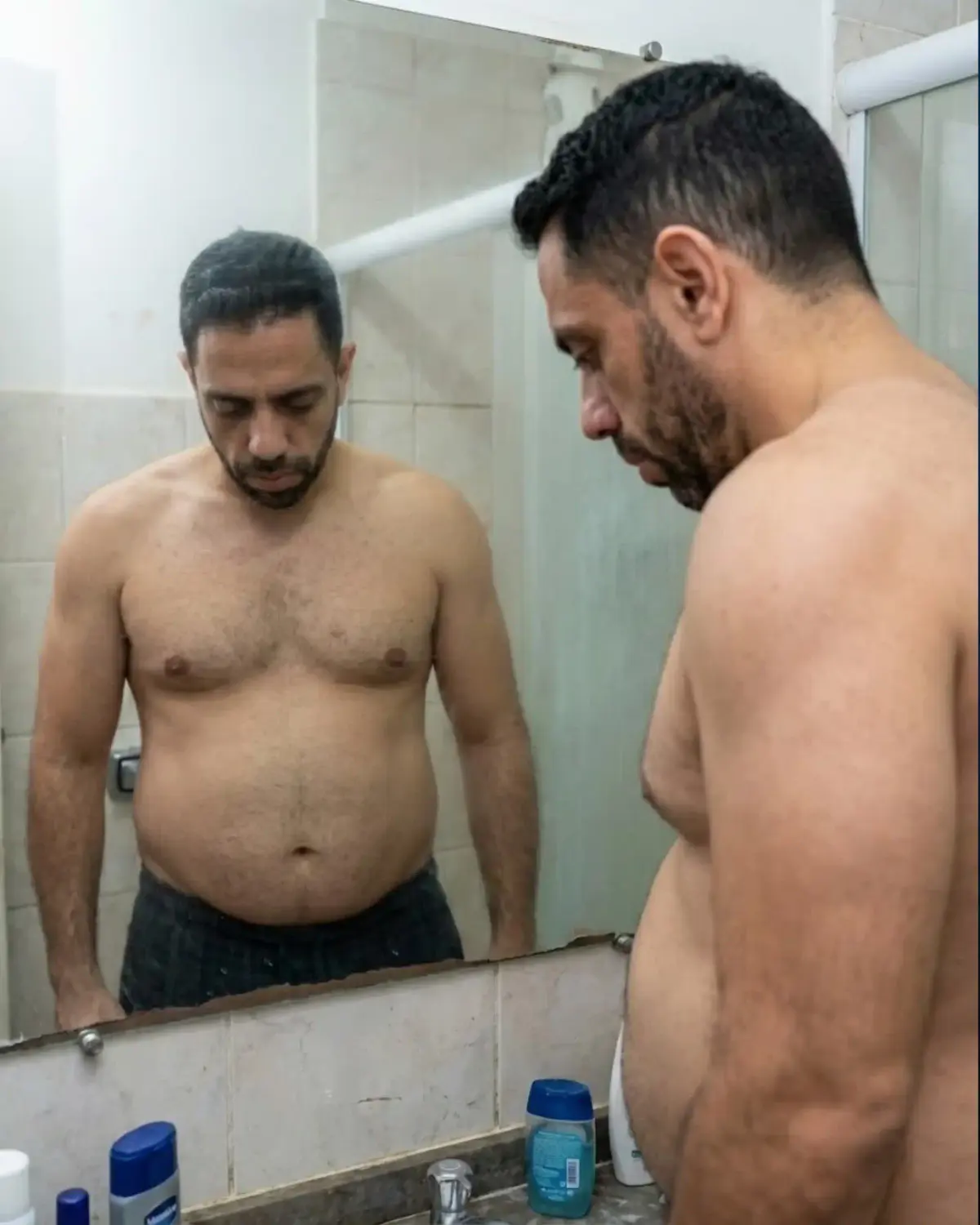 homens sem camisa olhando a própria barriga
