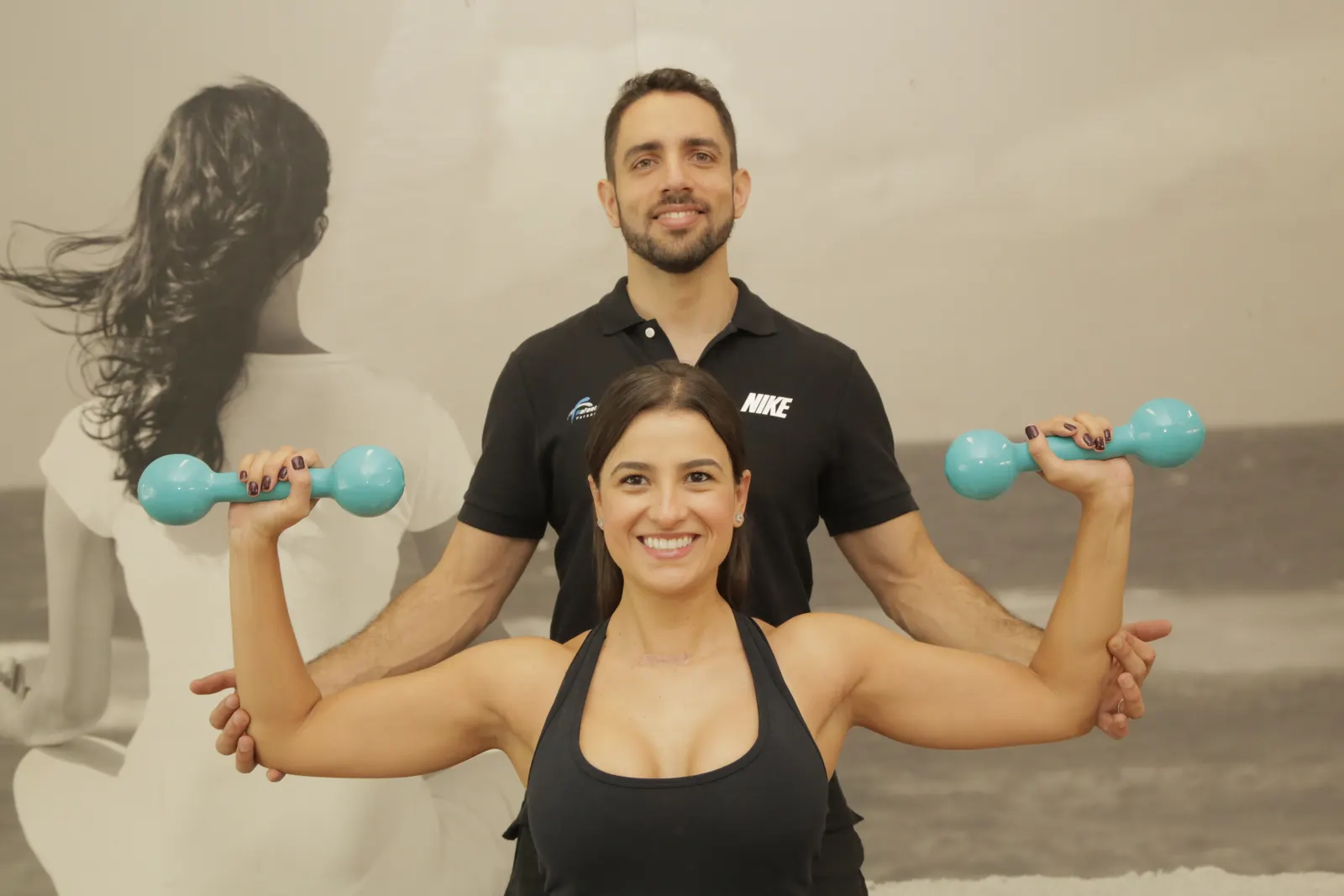 Rafael Figueiredo, personal trainer em Alphaville, corrigindo a execução de exercício com halteres de uma aluna