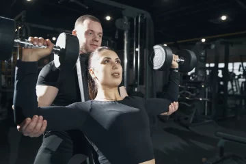 mulher treinando musculação com personal trainer- desenvolvimento de ombros