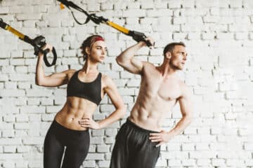 casal fazendo treinamento funcional com trx Athletic man and woman doing TRX workout at gym. Health and fitnes concept.