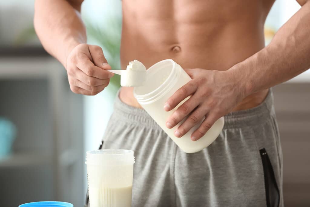 proteínas na recuperação muscular Sporty man making protein shake at home