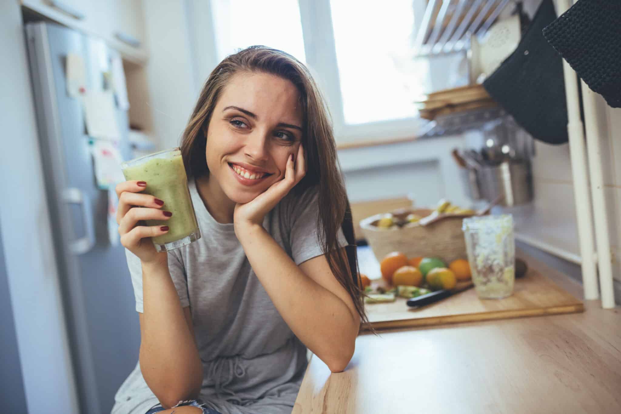 mulher tomando suco na cozinha aprendendo a comer conscientemente