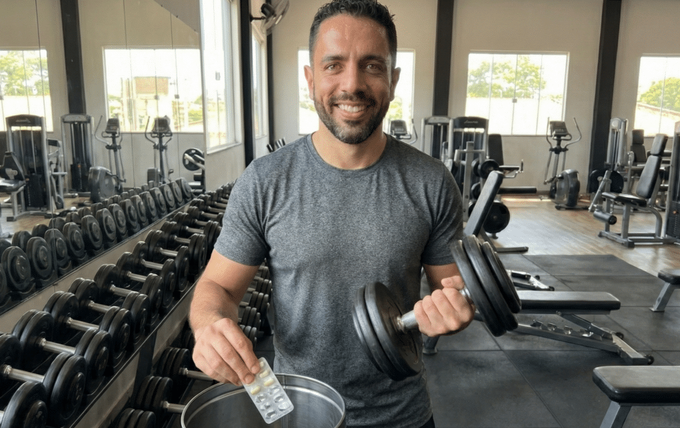Homem com halteres e comprimidos. exercício melhor que remédio para dor